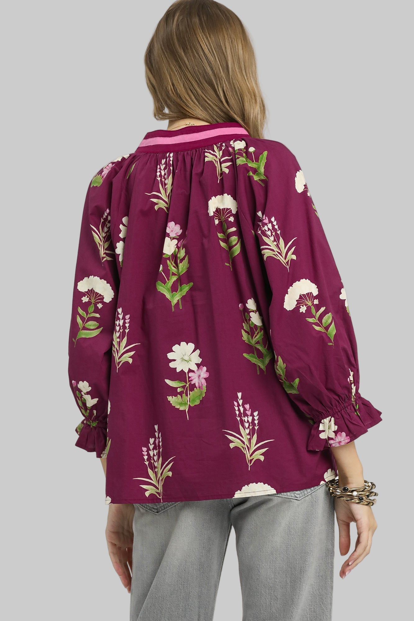 Person wearing a purple floral blouse on a gray background